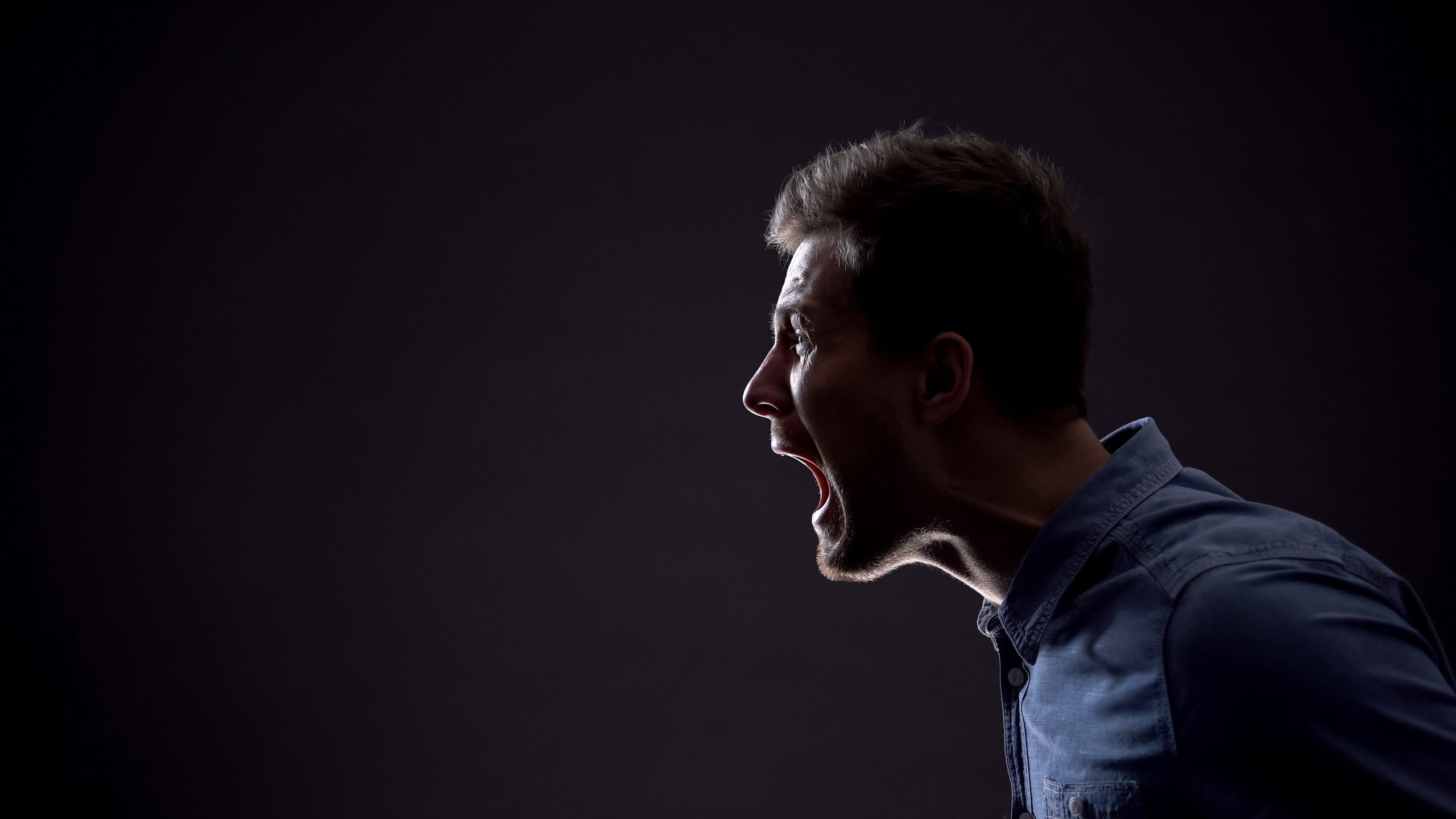 Frustrated man emotionally screaming isolated on black background, life problems